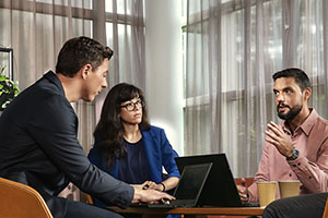 Professionals in een vergaderruimte bespreken ideeën rond een tafel met laptops
