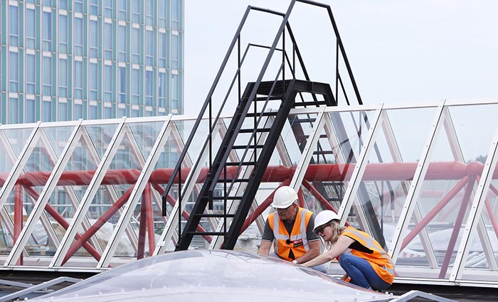 Taget på Almere Centrum railway station. Tagdækkere monterer ovenlyskupler og ovenlys.