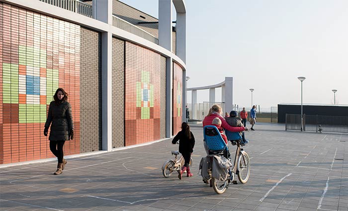 Kinder und Mutter außerhalb der Schule auf dem Spielplatz auf dem Heimweg