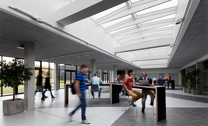 Busy school hall bathed in natural light through roof skylights and facade windows
