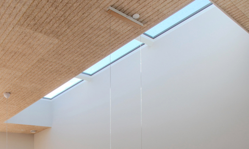 Moderne køkken i træ, oplyst af stort Modular Rooflights Linearlight over køkkenøen.