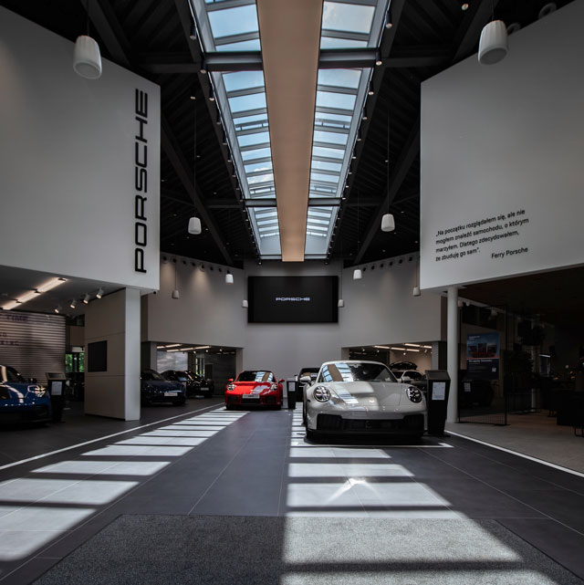 Moderne Porsche-udstillingslokale oplyst af høje VELUX-tagvinduer over sportsvogne.