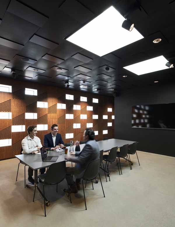 Trois personnes profitent d'une réunion de bureau avec la lumière du jour fournie par le toit.