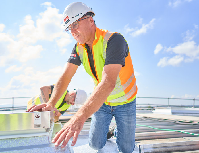 Een monteur veilig op het dak aan het werk