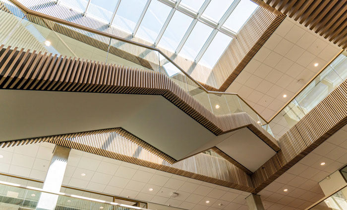 Atrium med VELUX-tagvindue, træpaneler og glasgelændere.