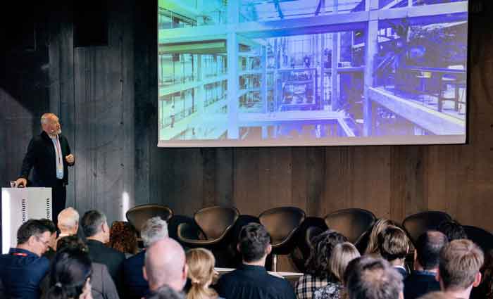 Vergaderzaal met deelnemers die naar een presentatie over architectuur kijken