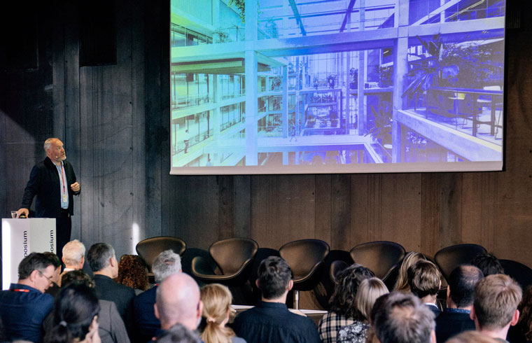 Vergaderzaal met deelnemers die naar een presentatie over architectuur kijken