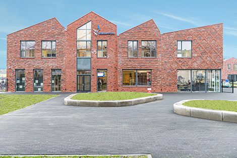 Modern onderwijsgebouw met een bakstenen gevel en grote ramen. Foto: Kasper Veenstra